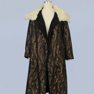 May include: A long black coat with a gold and black geometric pattern. The coat has a large white fur collar.