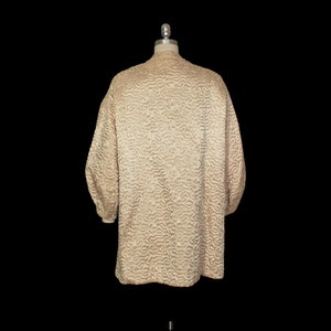 May include: A cream-colored quilted jacket with a textured pattern. The jacket has long sleeves and a collar.