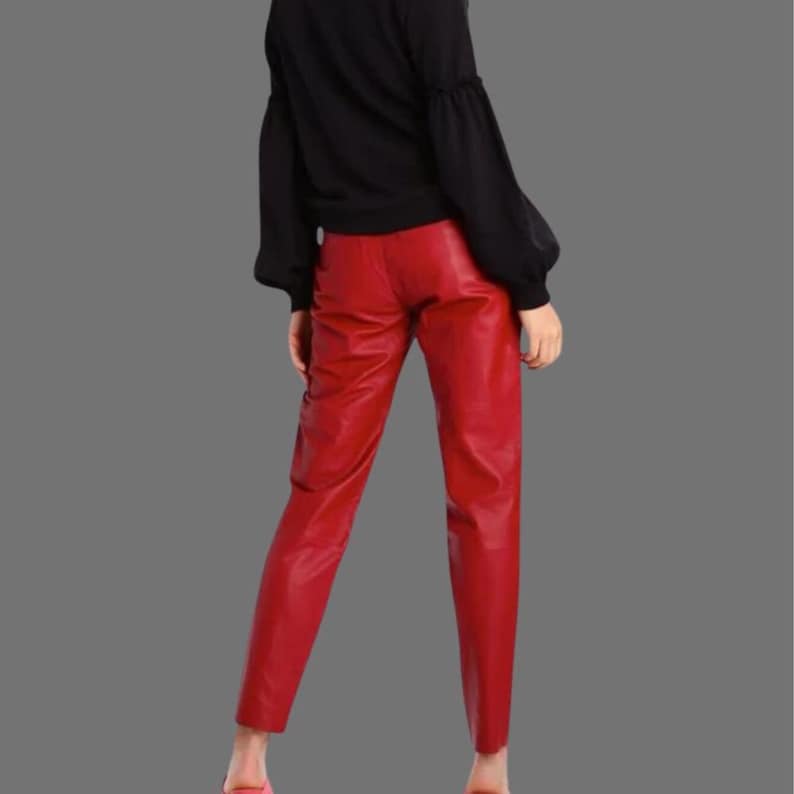 May include: Red leather pants with a straight leg cut. The pants are a vibrant red color and appear to be made of a smooth leather material. The pants are paired with a black top.