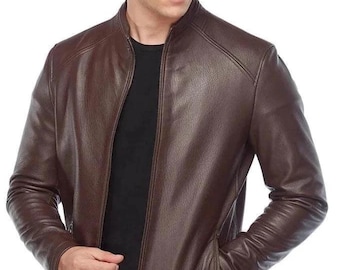 Puede incluir: Chaqueta de cuero marrón con cuello alzado y cierre de cremallera. La chaqueta tiene dos bolsillos delanteros y un corte entallado. El cuero parece liso y tiene un ligero brillo. La chaqueta es de color marrón medio.