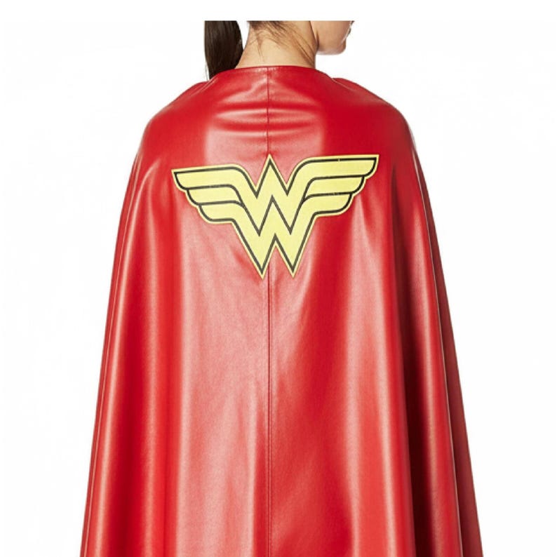 May include: A red cape with a yellow emblem featuring a stylized "W" with wings. The cape is made of a smooth material and drapes down the back. The emblem is centered on the upper back of the cape.