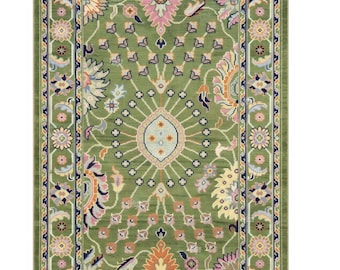May include: A rectangular green rug with an intricate floral design. The rug features a central medallion and a border with repeating floral patterns in shades of pink, orange, and blue. The rug has a fringe on the short ends.