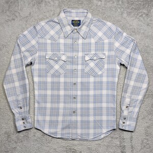 May include: A light blue and white plaid button-down shirt with long sleeves. The shirt has two chest pockets and a pointed collar. The brand name "NELSON" is visible on a small tag near the collar.
