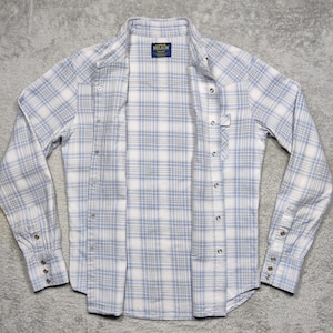 May include: A light blue and white plaid button-down shirt with long sleeves. The shirt has a classic collar, snap closures, and a small label that reads "NELSON". The shirt is open, displaying the interior.