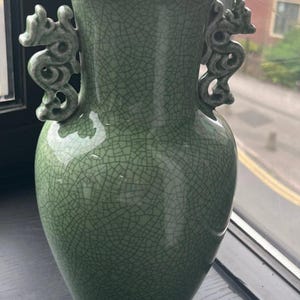 A finely crafted green crackle-glazed vase with dragon-shaped handles on either side