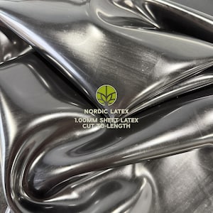 May include: A sheet of black latex with a glossy, reflective surface. The material is folded, creating deep curves and highlights. Text printed on the surface reads: NORDIC LATEX 1.00MM SHEET LATEX CUT TO LENGTH, accompanied by a green circular logo.