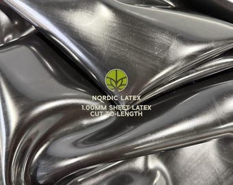 May include: A sheet of black latex with a glossy, reflective surface. The material is folded, creating deep curves and highlights. Text printed on the surface reads: NORDIC LATEX 1.00MM SHEET LATEX CUT TO LENGTH, accompanied by a green circular logo.