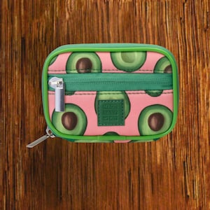 Pink Background with Green Avocado travel pill organizer case closed, compact zippered medication pouch for daily use, portable storage for vitamins and prescriptions.