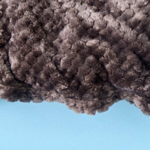 Close-up of plush textured throw blanket fabric in campfire, showing the soft rosette pattern.