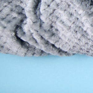 Close-up of plush textured throw blanket fabric in dove grey, showing the soft rosette pattern.