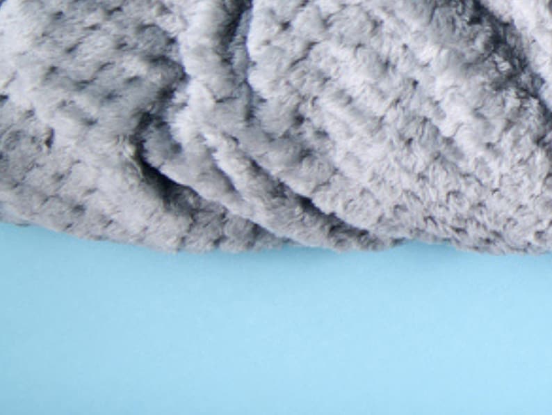 Close-up of plush textured throw blanket fabric in dove grey, showing the soft rosette pattern.