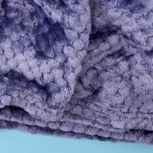 Close-up of plush textured throw blanket fabric in lilac, showing the soft rosette pattern.