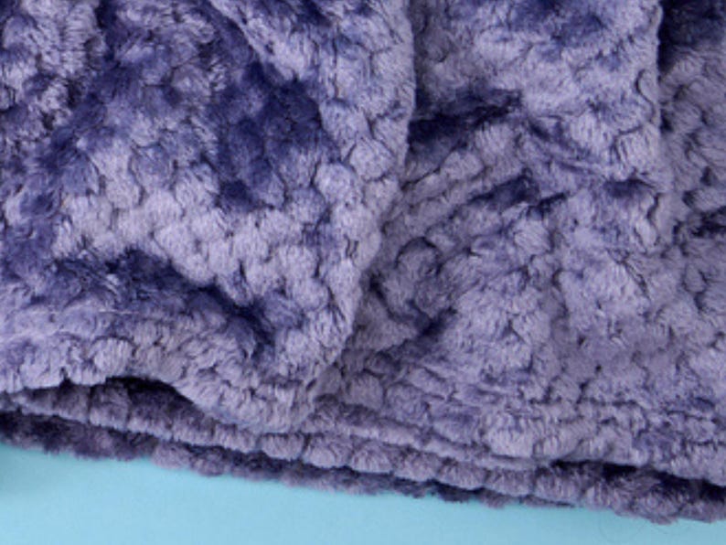 Close-up of plush textured throw blanket fabric in lilac, showing the soft rosette pattern.