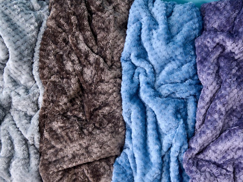 Plush textured throw blanket with a soft rosette pattern, available in dove grey, campfire, ash blue, or lilac — one color included per order.