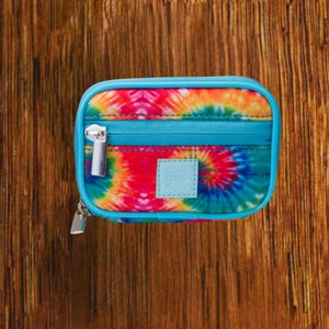 Tie Dye travel pill organizer case closed, compact zippered medication pouch for daily use, portable storage for vitamins and prescriptions.