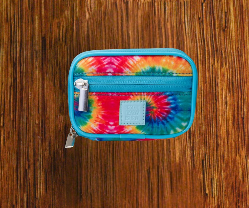 Tie Dye travel pill organizer case closed, compact zippered medication pouch for daily use, portable storage for vitamins and prescriptions.