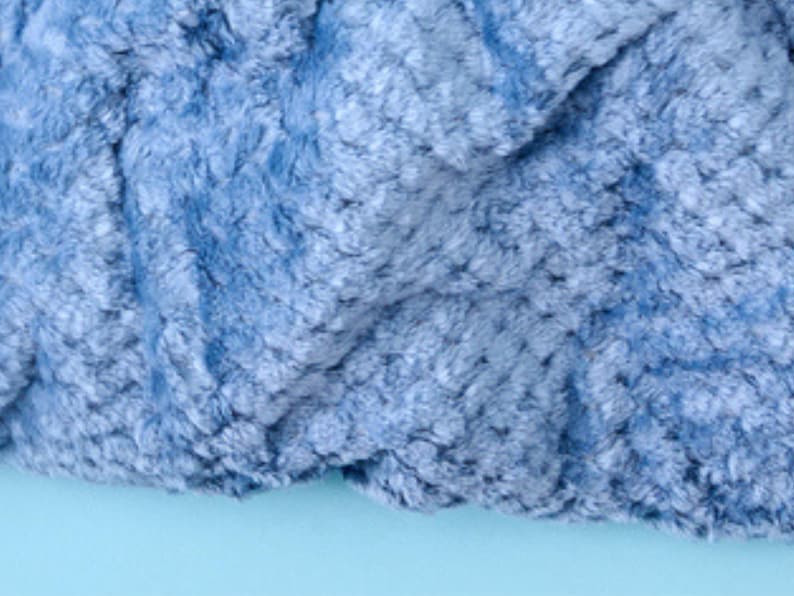 Close-up of plush textured throw blanket fabric in ash blue, showing the soft rosette pattern.