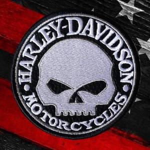 Puede incluir: Un parche bordado circular que presenta un gráfico de calavera plateada centrado dentro de un borde negro. El texto Harley-Davidson Motorcycles está bordado en letras mayúsculas blancas alrededor del emblema circular.
