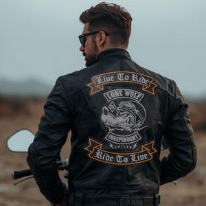 Peut inclure: Une veste en cuir noir avec un grand écusson au dos portant le texte Live To Ride et Ride To Live. L'écusson présente un graphique représentant un loup portant des lunettes et un casque, avec les mots Lone Wolf Independent Outlaw en blanc.