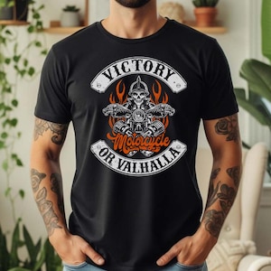 Könnte beinhalten: Schwarzes T-Shirt mit Motorrad-Grafik. Das Design zeigt einen Schädel auf einem Motorrad, umgeben von Flammen, und die Worte "Victory or Valhalla". Der Text ist in Weiß und Orange gehalten.