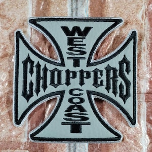 Puede incluir: Un parche termoadhesivo de color gris claro con forma de cruz de hierro, con bordes y letras bordadas en negro. El texto dice West Coast Choppers, con West Coast dispuesto verticalmente y Choppers horizontalmente en el centro.