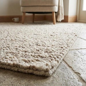 May include: A rectangular area rug featuring a thick, chunky knit texture in a neutral off-white and light beige color palette. The rug is constructed from large, looped yarn fibers that create a dense, uneven surface with a visible, tactile weave.