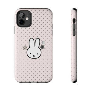 May include: A phone case with a light pink background covered in small gray polka dots. The case features a white cartoon rabbit with a black outline and two gray stars. The case is designed to fit a smartphone.