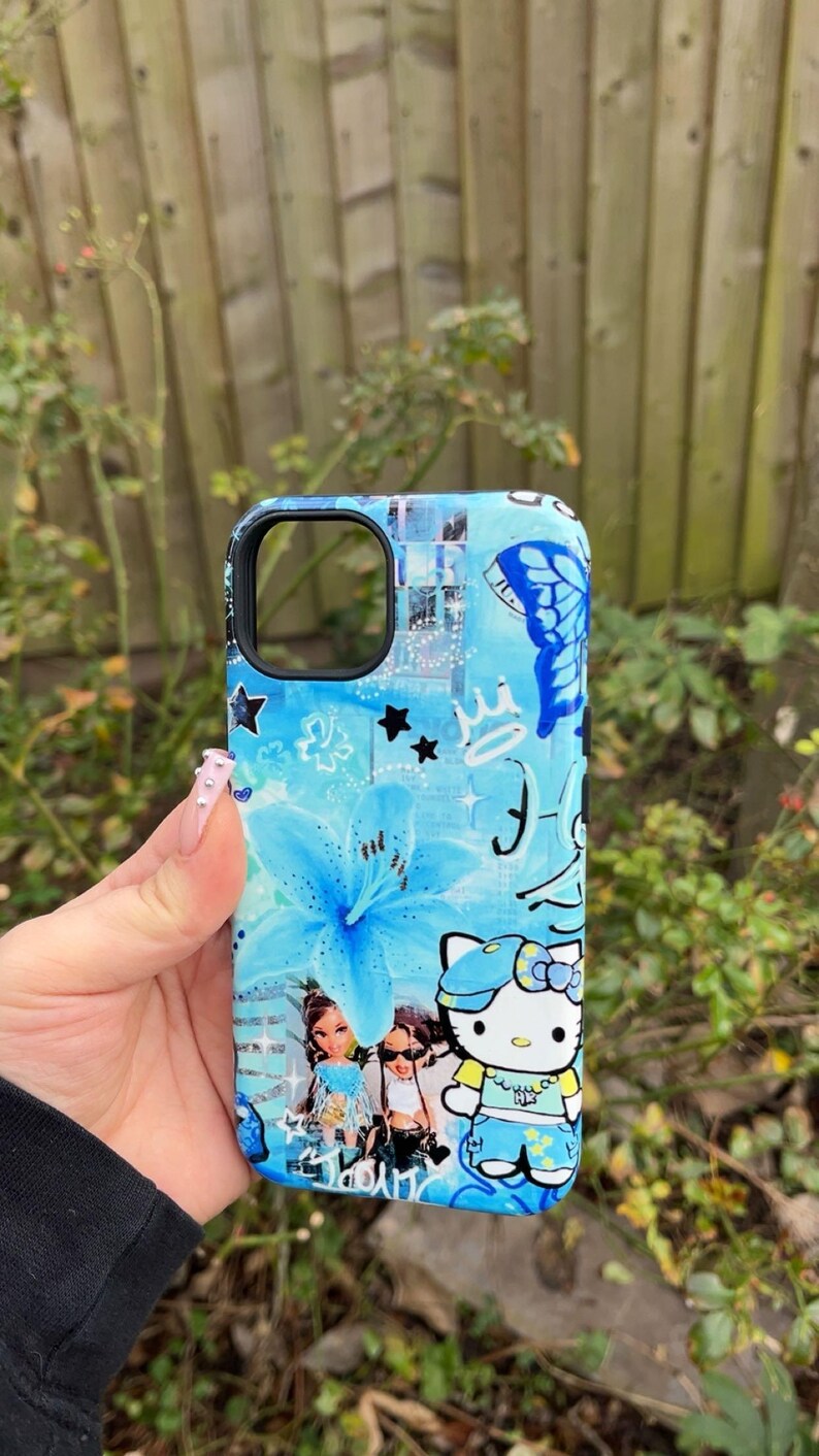 K&ouml;nnte beinhalten: Eine blaue Handyh&uuml;lle mit floralem Design, Schmetterlingen, Sternen und einer Hello Kitty-Grafik. Die H&uuml;lle hat einen schwarzen Rand. Das Design beinhaltet Blau- und Wei&szlig;t&ouml;ne. Die H&uuml;lle wird in einer Hand gehalten.