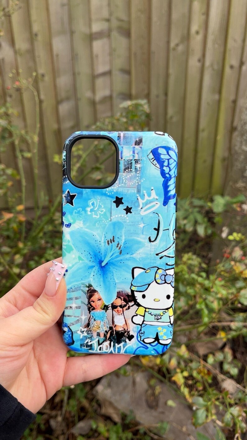 K&ouml;nnte beinhalten: Eine blaue Handyh&uuml;lle mit floralem Design, Sternen und einem Schmetterling. Die H&uuml;lle enth&auml;lt auch Illustrationen von Bratz-Puppen und Hello Kitty. Die H&uuml;lle hat einen schwarzen Rand.
