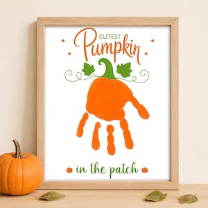 May include: A framed print featuring an orange handprint shaped like a pumpkin with a green stem and leaves. The text reads Cutest Pumpkin in the patch in orange and green script. Four small orange stars and two small orange pumpkins are included.