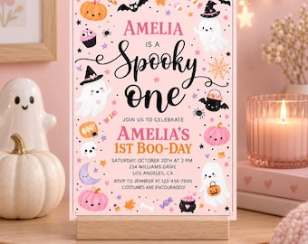 Puede incluir: Una tarjeta de invitación rectangular rosa con el texto AMELIA IS A SPOOKY ONE, AMELIA'S 1ST BOO-DAY y detalles del evento. El diseño incluye ilustraciones de fantasmas, calabazas, murciélagos, una araña, una calavera, una luna y dulces.