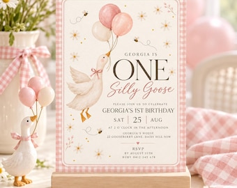Puede incluir: Una tarjeta de invitación de cumpleaños rectangular con borde de cuadros vichy rosa, con una oca blanca que sostiene tres globos, margaritas y abejas. El texto dice: Georgia is ONE Silly Goose, Georgia's 1st Birthday, Sat 25 Aug, 2 o'clock, 22 Gooseberry Lane, RSVP by August 15th, Ruby 0412 345 678.