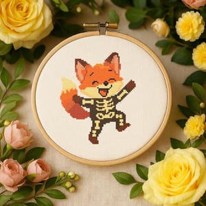 May include: A cross-stitch embroidery hoop featuring a cartoon fox in an orange and white skeleton costume. The fox is smiling and has its arms raised. The embroidery is set in a wooden hoop and surrounded by yellow and pink roses.