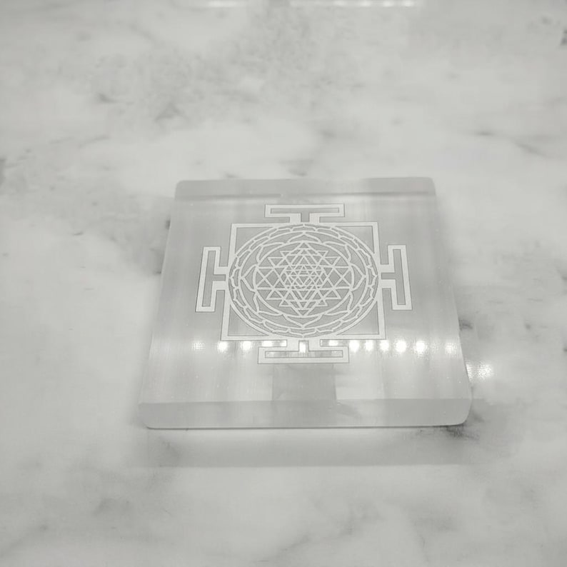Natural white selenite grid featuring an intricate central Shri Yantra symbol surrounded by sacred geometric elements.