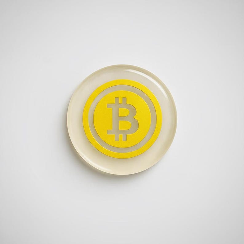 Close-up detail shot of the smooth epoxy resin edge and metallic yellow Bitcoin logo embedded inside the physical coin token.