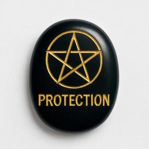 May include: A black, oval-shaped stone featuring a gold pentagram within a circle, with the word "PROTECTION" in gold. The stone has a smooth, polished finish. The design is carved into the surface.