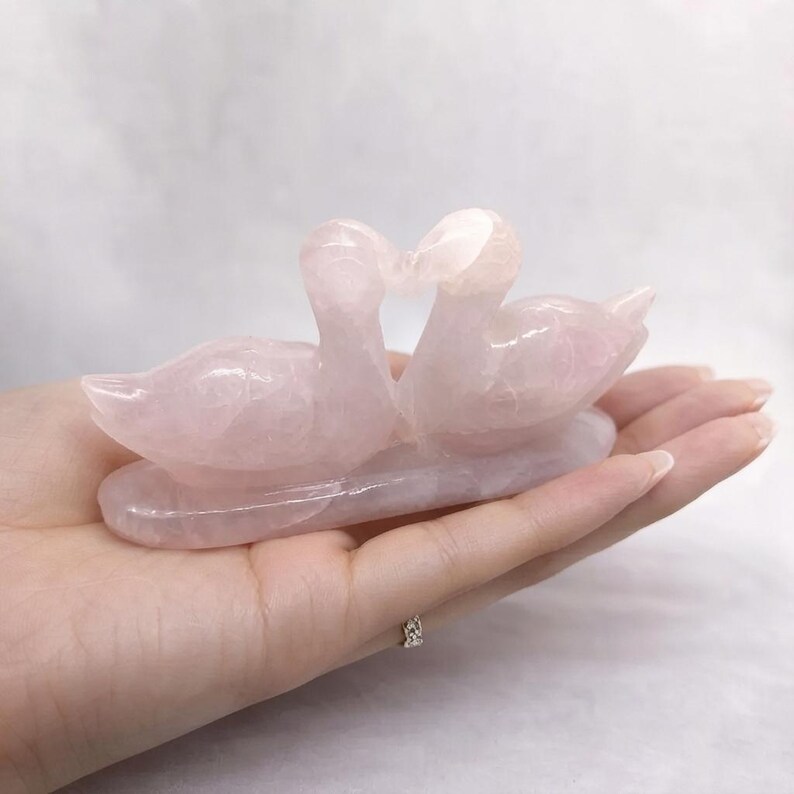 Front angle of the natural pink rose quartz couple sculpture capturing the detailed carving and delicate heart cutout between the birds.
