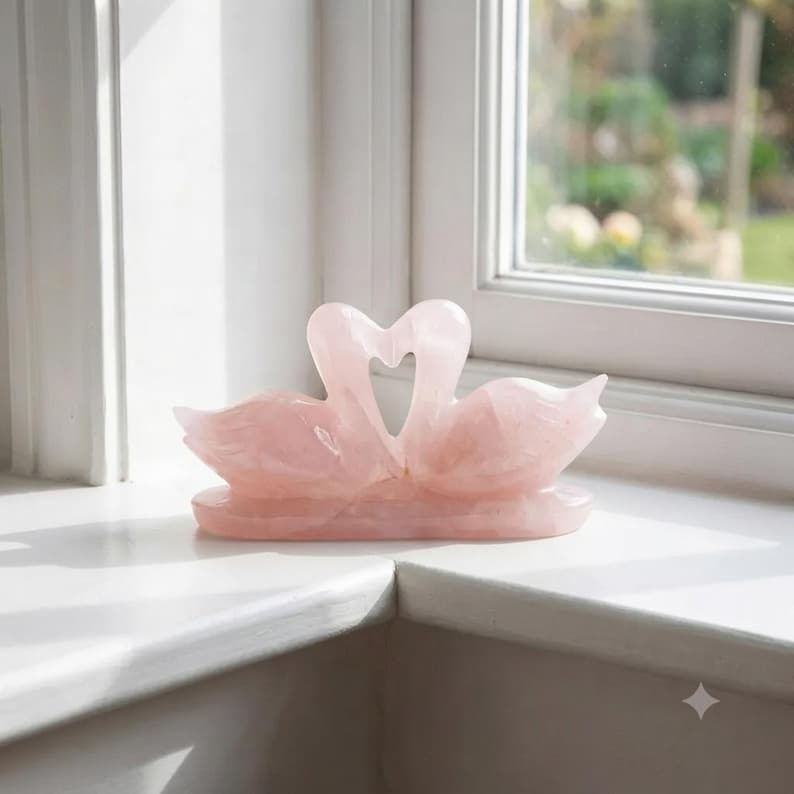 Close-up view of a hand-carved rose quartz love birds crystal sculpture showing smooth polished natural pink gemstone details.
