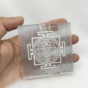 Shri Yantra crystal grid plate made from translucent white selenite with polished edges and detailed laser engraving.