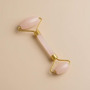 Natural rose quartz crystal facial roller for gentle massage during moisturizer application