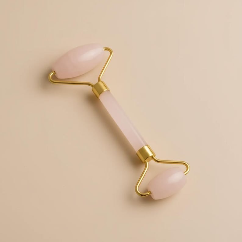 Natural rose quartz crystal facial roller for gentle massage during moisturizer application