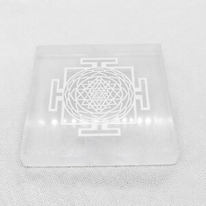 Close-up of Shri Yantra sacred geometry engraving on a polished translucent white selenite crystal charging plate.