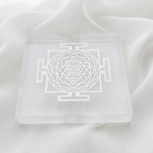 Square white selenite charging plate engraved with a detailed Shri Yantra sacred geometry design for crystal grid and altar decor.