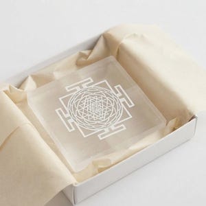 Natural selenite Shri Yantra plate featuring geometric engraving on a translucent white square crystal charging board.