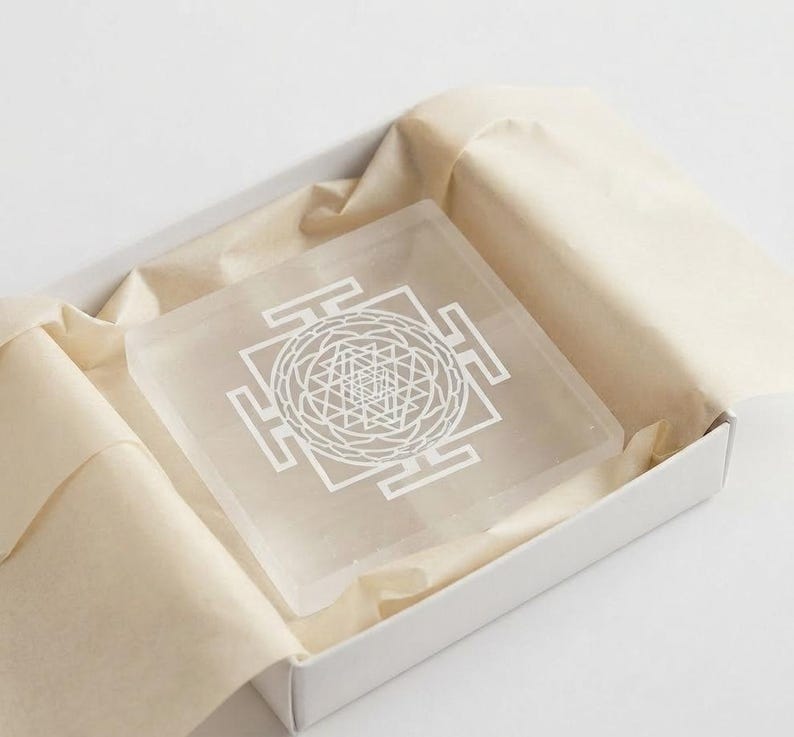Natural selenite Shri Yantra plate featuring geometric engraving on a translucent white square crystal charging board.