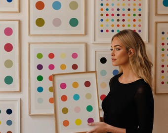 May include: A collection of framed art prints featuring colorful polka dot patterns. The prints are in various sizes and arrangements, with dots in shades of red, yellow, blue, green, and pink. The frames are a natural wood color.