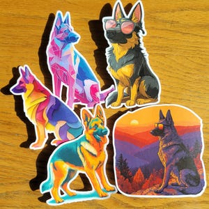 May include: A collection of five German Shepherd dog stickers. The stickers feature colorful, stylized illustrations of the dogs, including one wearing sunglasses and another set against a sunset landscape. The stickers are on a wooden surface.
