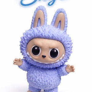 May include: A collectible figurine of a creature in a fuzzy, light purple bunny suit with large, black eyes and a toothy grin. The figurine has tan ears and feet. The name "Skye" is written above the figure in a stylized, light blue font.