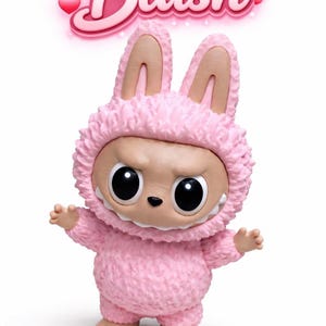 May include: A pink figurine of a creature in a bunny suit with the word "Blush" above it. The figure has large black eyes, a small nose, and a toothy grin. The bunny suit is textured and fluffy.