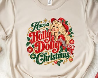 May include: A beige short-sleeve t-shirt featuring a graphic of a blonde woman in a red cowboy hat. The text reads Have a Holly Dolly Christmas, surrounded by red and green ornaments, holly leaves, and candy canes in a festive design.